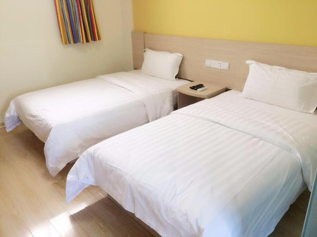 南京7天酒店南京鼓楼云南路地铁站店的配有白色床单的酒店客房内的两张床