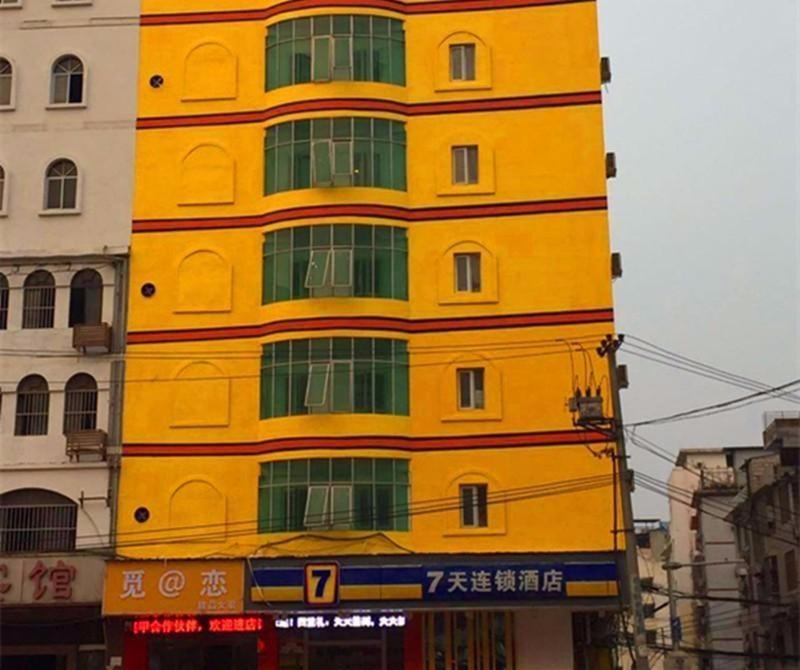 南宁7天酒店·南宁江南客运站地铁口店的一座黄色建筑,设有绿色的窗户
