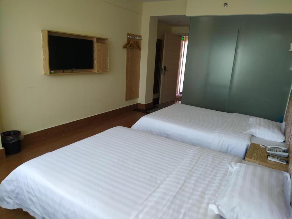 三亚7天酒店三亚亚龙湾景区店的配有电视的酒店客房内的两张床