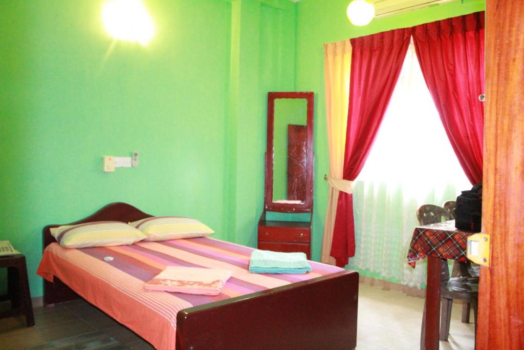 WarakapolaWijaya Tourist INN的一间卧室设有一张带绿色墙壁和窗户的床。