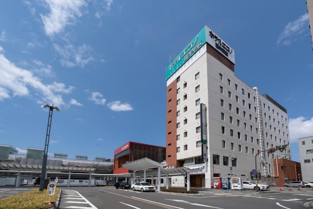 福井爱科诺福井站前酒店的街道拐角处高大的白色建筑