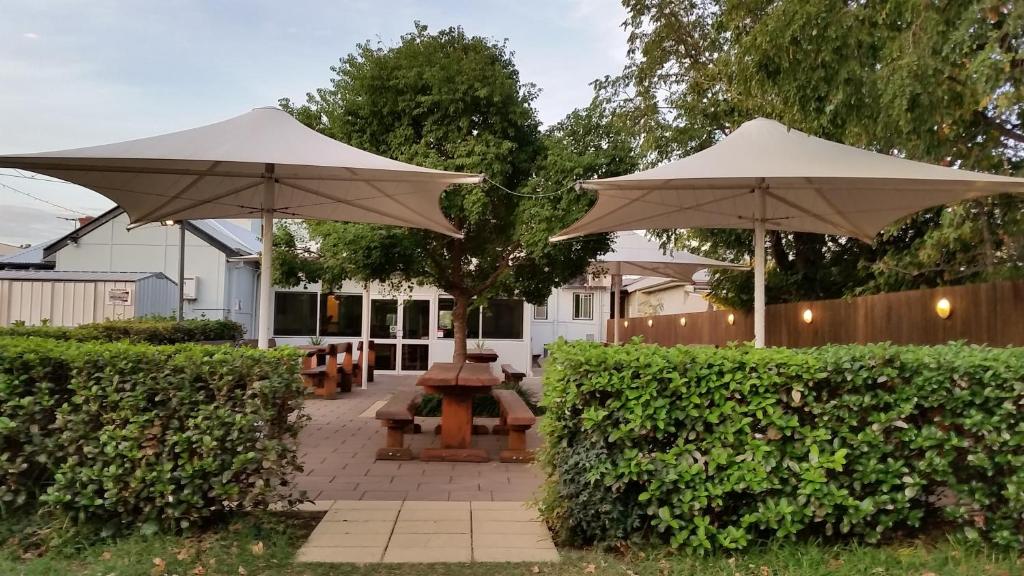 KootingalKootingal Hotel的桌子和长凳上两把白色遮阳伞