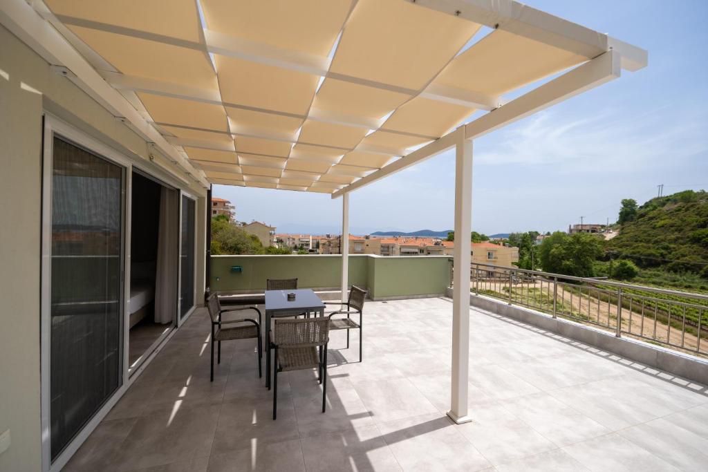 尼亚普拉莫斯Lofos Apartments的阳台的天井配有桌椅