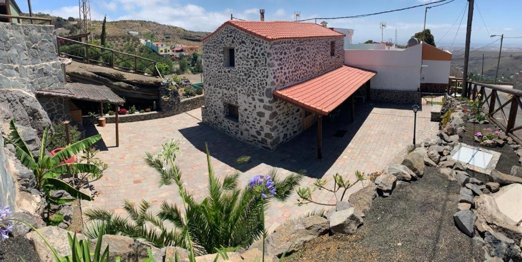 特尔德Casa Canaria的一座石头建筑,有红色的屋顶和一些植物