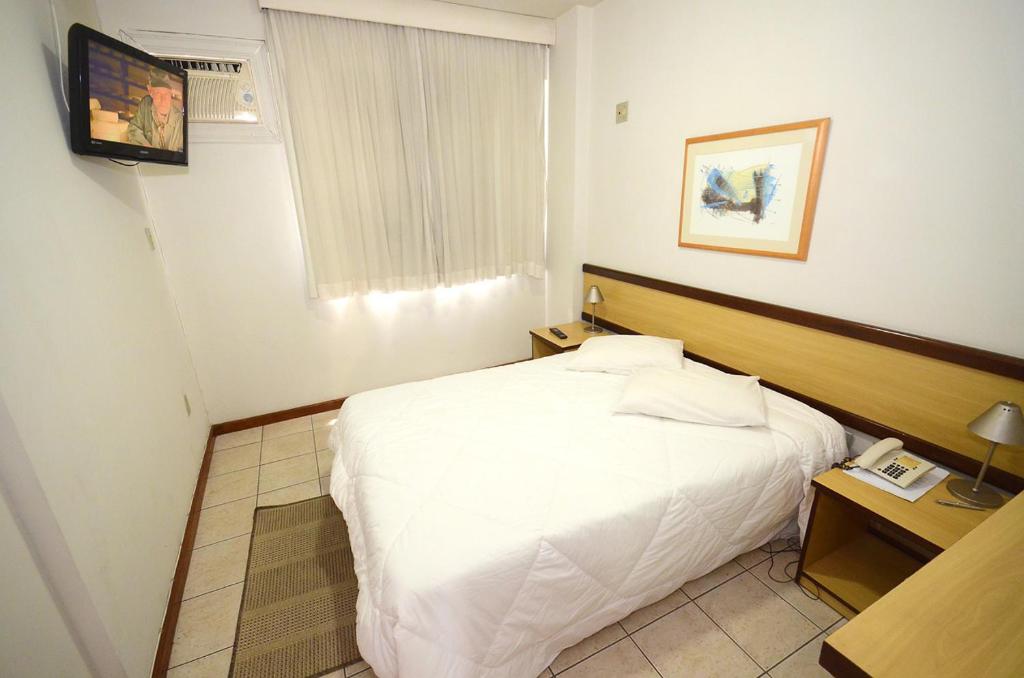尤西德福拉Solar Flat Hotel的卧室配有白色的床和电视。