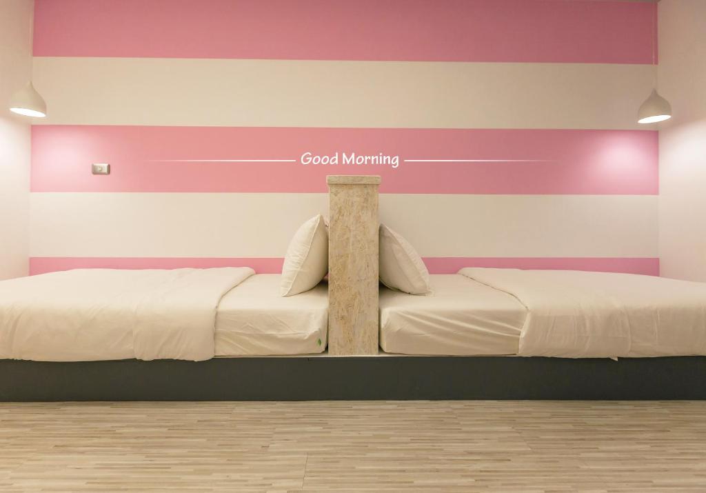 花莲市花莲北吉光轻旅青年旅馆的一间卧室,配有两张床和一个读书好早晨的标志