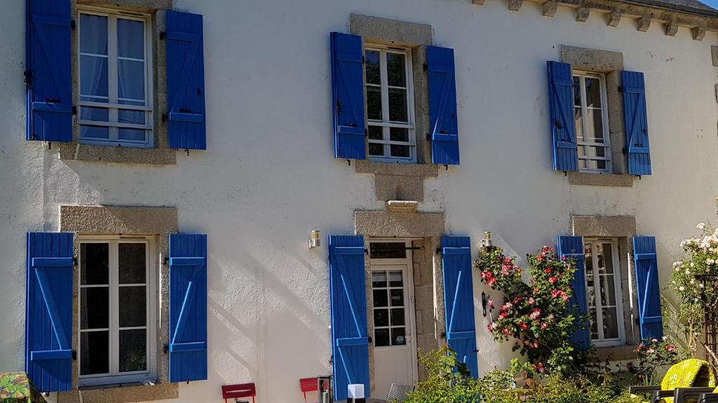 ElliantNuances bretonnes的白色的建筑,有蓝色百叶窗和鲜花