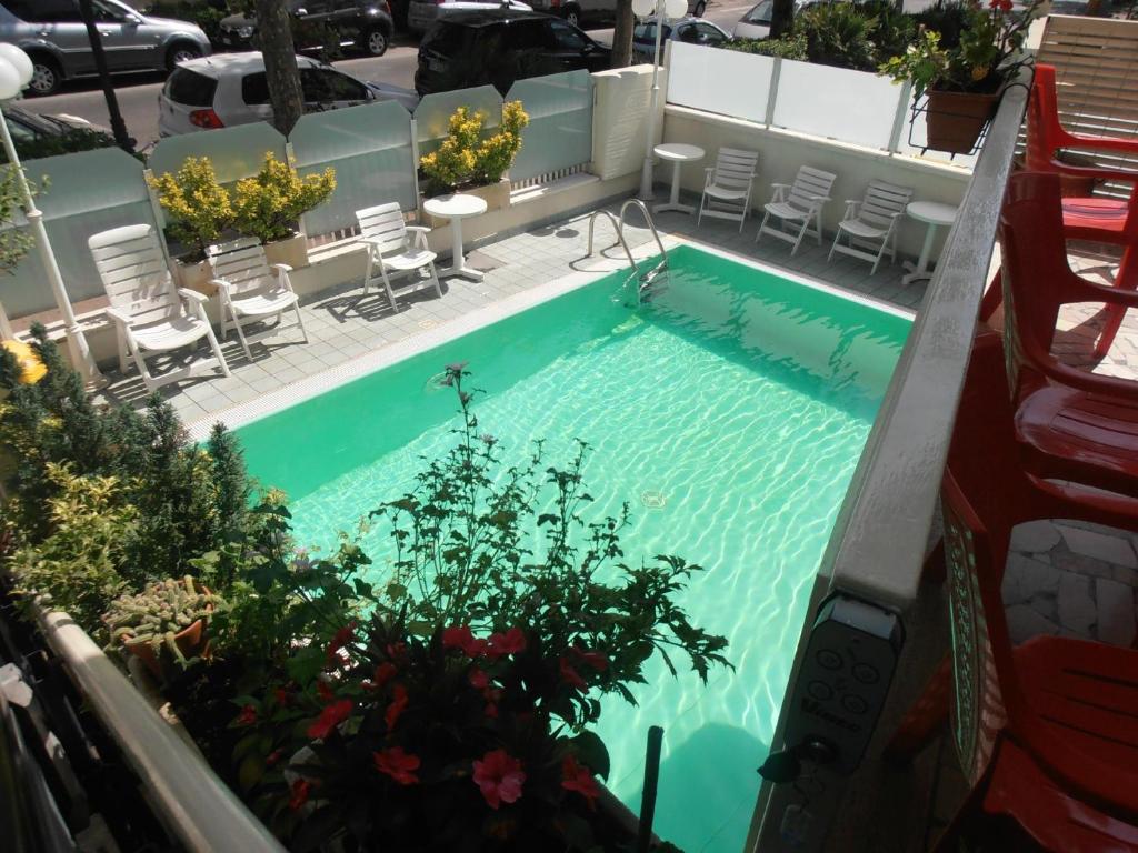 里米尼Hotel Arno的享有带椅子和植物的游泳池的顶部景致