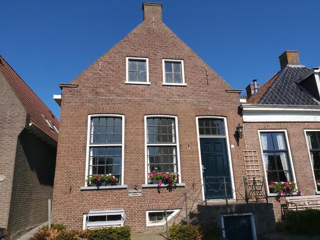 斯塔福伦De Wachtkaemer in De olde banck的红色砖屋,阳台上装有窗户和鲜花