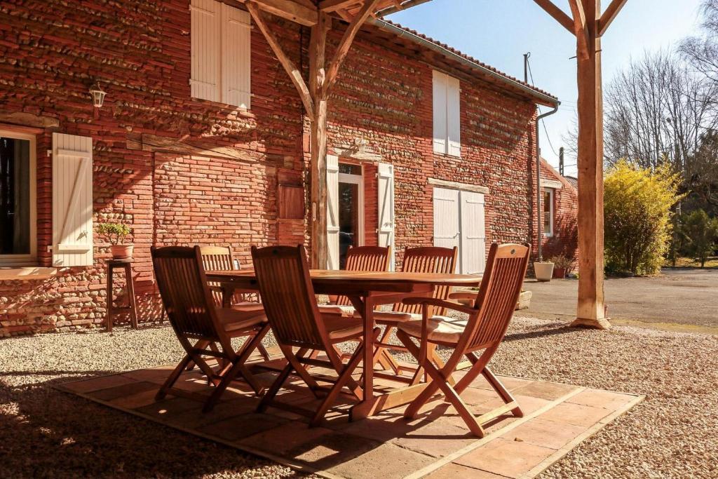 Montesquieu-VolvestreGîte rural Aqui-naut的砖砌建筑前的木桌和椅子