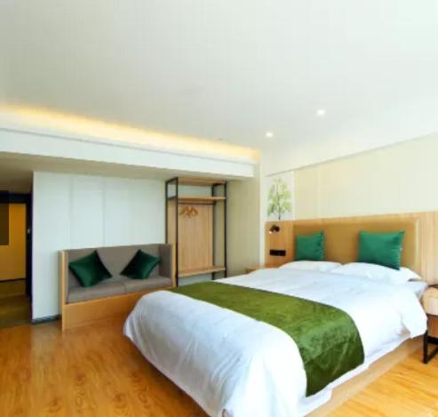 南京GreenTree Inn Nanjing Lukou Airport的卧室配有带绿色枕头的大型白色床