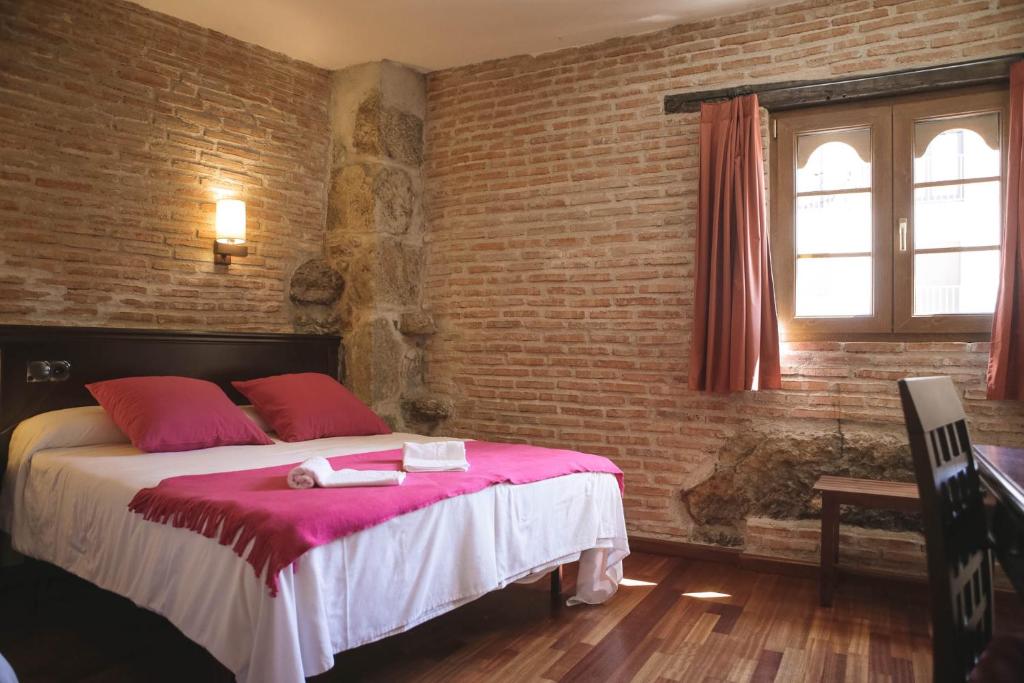 坎德拉里奥Hospedium Hotel La Fuente的一间卧室配有一张带红色枕头的床和砖墙