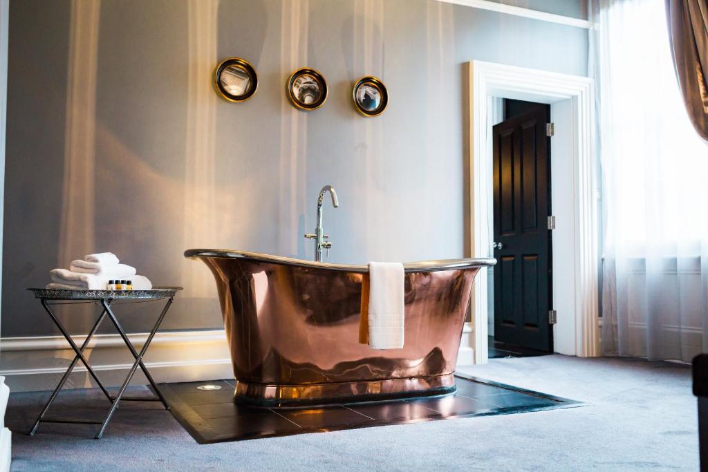 伊利诗人之家酒店的墙上设有铜浴缸的浴室