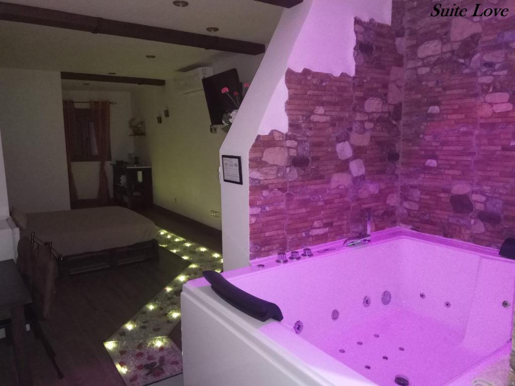 UcedaSuite Love Jacuzzi (Casas Toya)的砖墙房间里的一个粉红色的浴缸