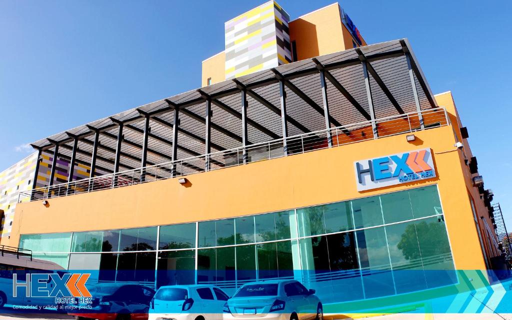 埃斯特利Hotel Hex Estelí的一座黄色的建筑,前面有汽车停放