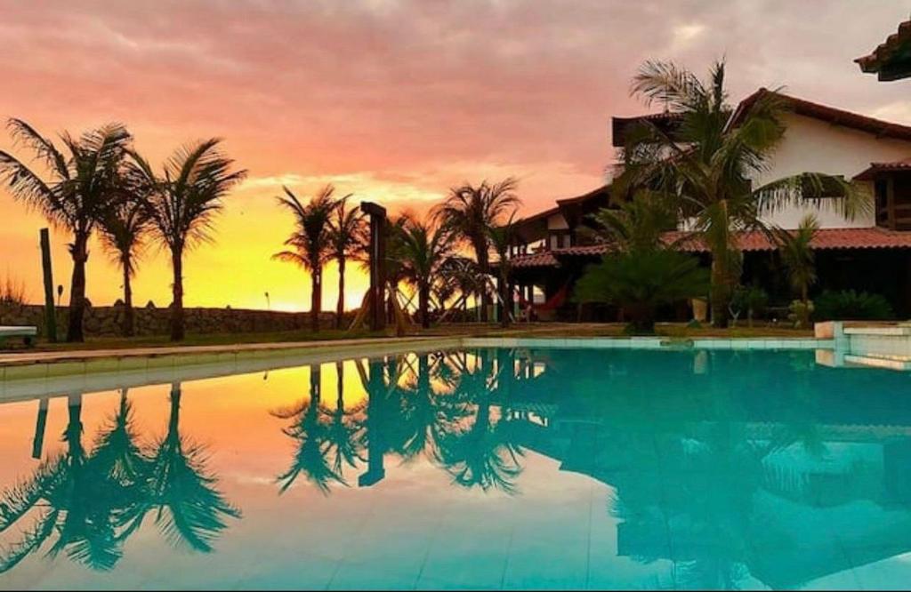 萨夸雷马Oceanica 1000 Beachfront Suites的棕榈树和日落的游泳池