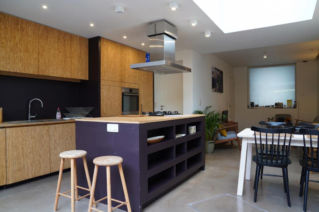 根特Well-situated and Comfortable Home的厨房设有1个带酒吧凳和桌子的岛屿