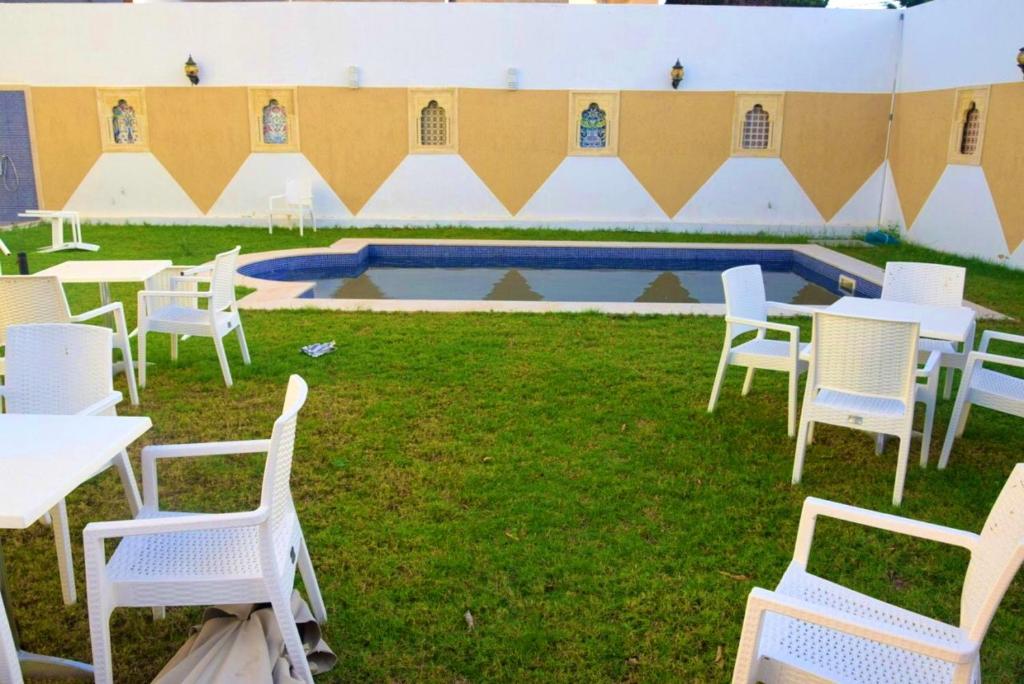 莫纳斯提尔5 bedrooms villa at Monastir 200 m away from the beach with private pool enclosed garden and wifi的一组白色的桌椅和一个游泳池