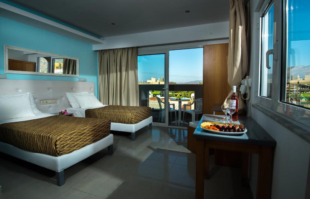 玛利亚Kastro Beach Apartments的酒店客房设有两张床和一张带一盘食物的桌子。
