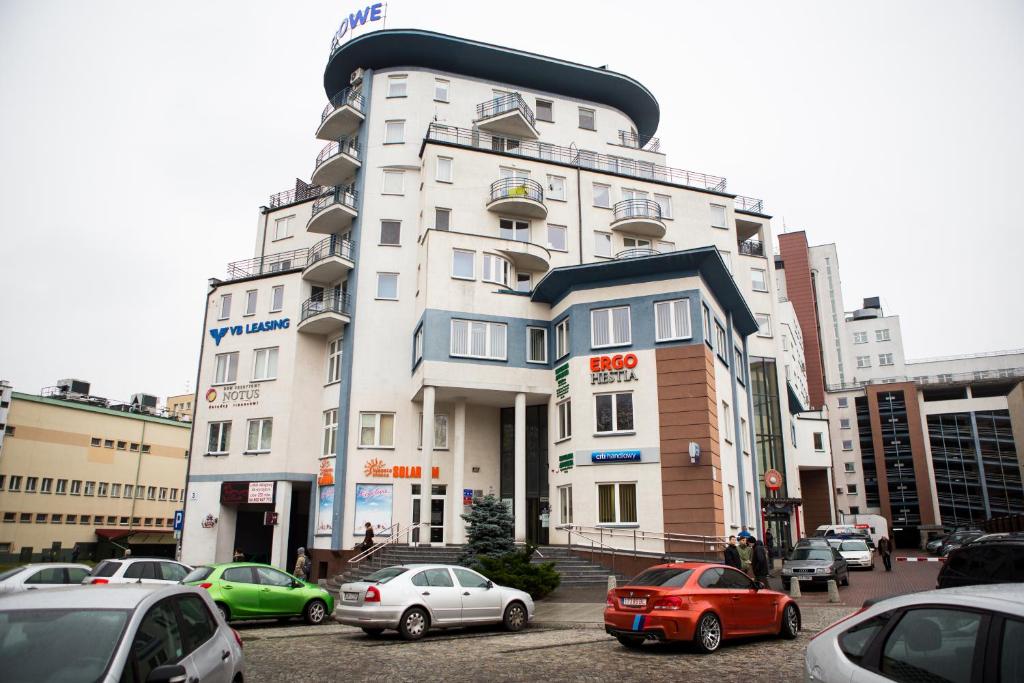 比亚韦斯托克Apartamenty Centrum的一座高大的白色建筑,前面有汽车停放
