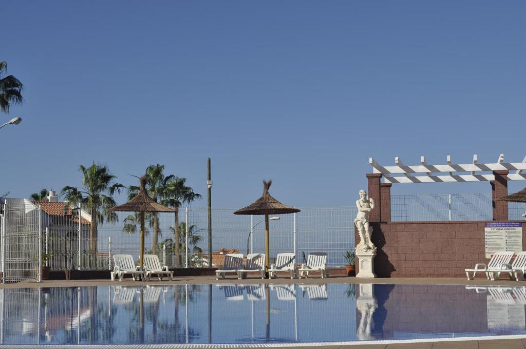 阿德耶Confort Villas Canarias的一个带椅子和遮阳伞的游泳池以及大海