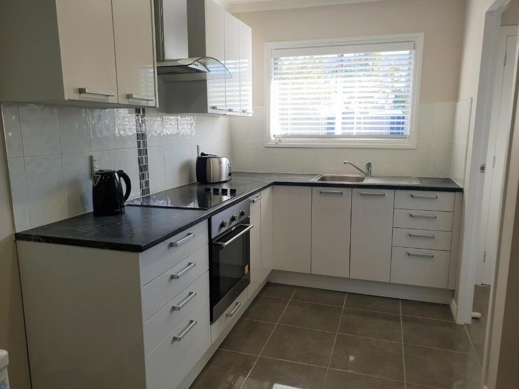 罗托鲁瓦Rose Apartments Unit 1 Central Rotorua-Accommodation&Spa的厨房配有白色橱柜和黑色台面