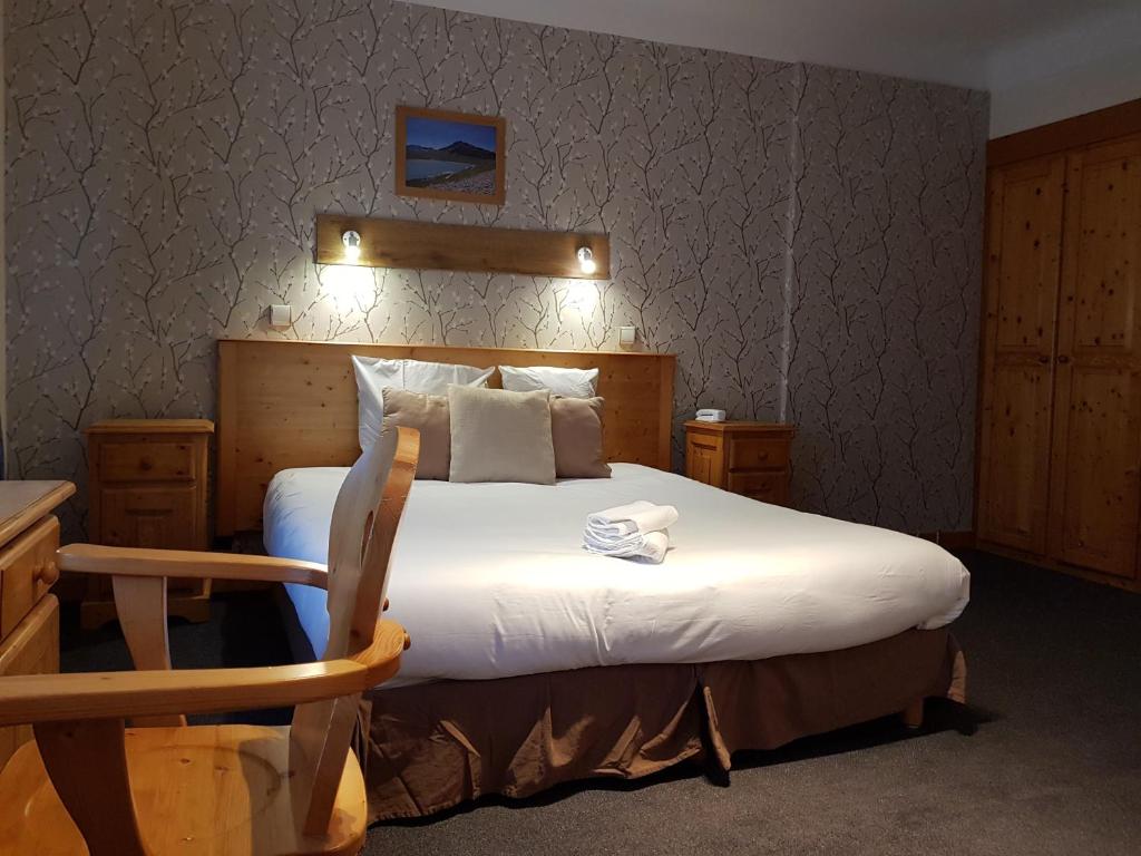 圣米歇尔德莫里耶讷Savoy Hotel & Restaurant的一间卧室配有一张大床和木制床头板