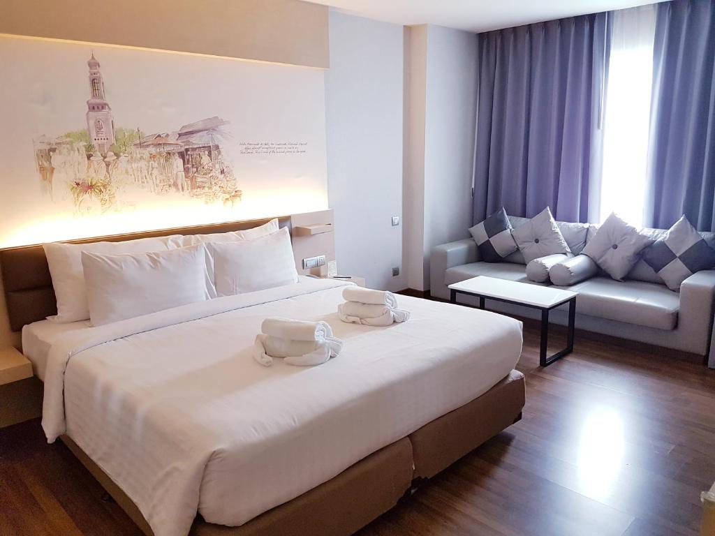 曼谷派瑞达酒店的酒店客房设有一张大床和一张沙发。