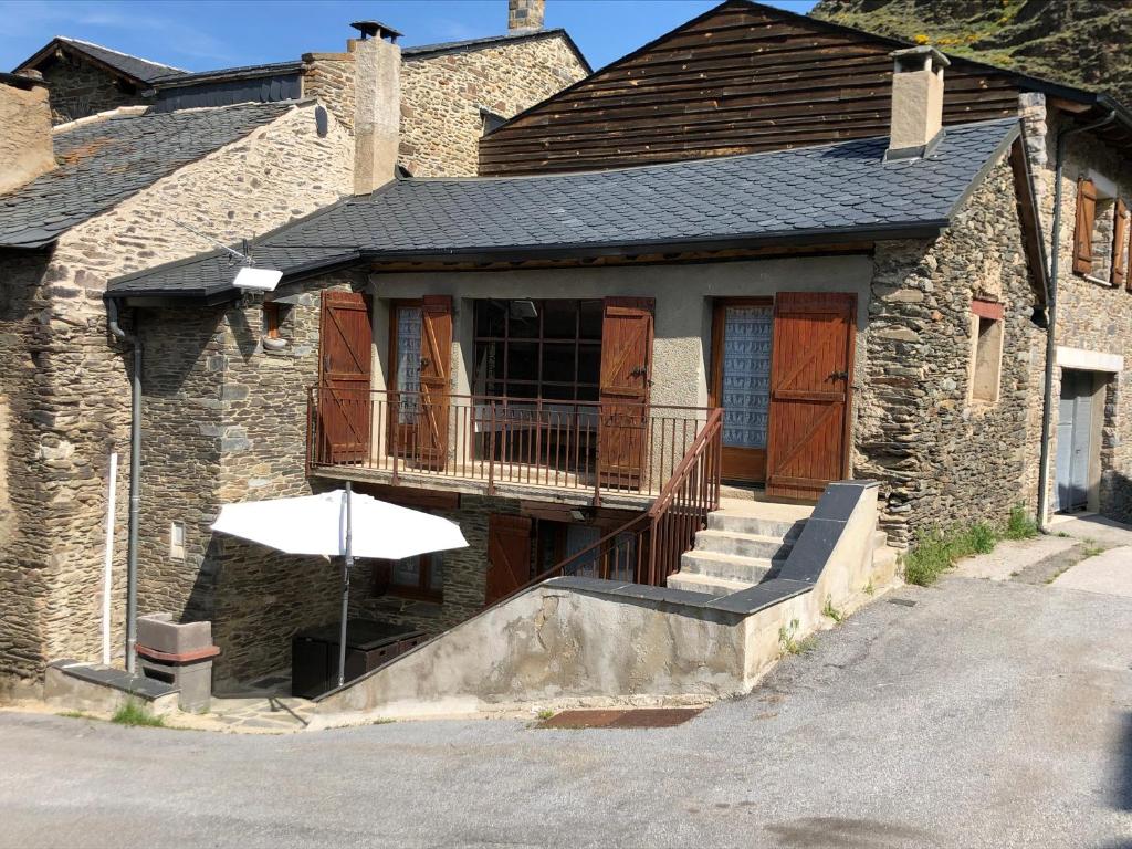 ValcebollèreMaison Olivotto的带阳台和遮阳伞的石头房子