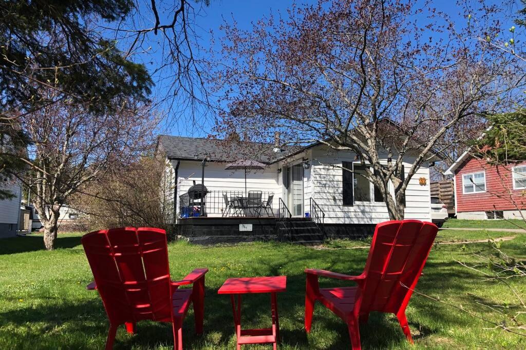希迪亚克Cozy chalet near the beach的两把红色椅子坐在房子前面的草上