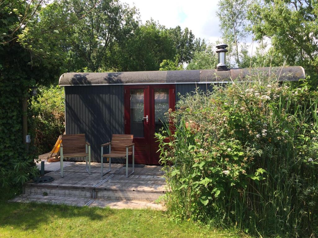 Velserbroek Gipsy wagon near Amsterdam and beach的门廊上带两把椅子的小房子