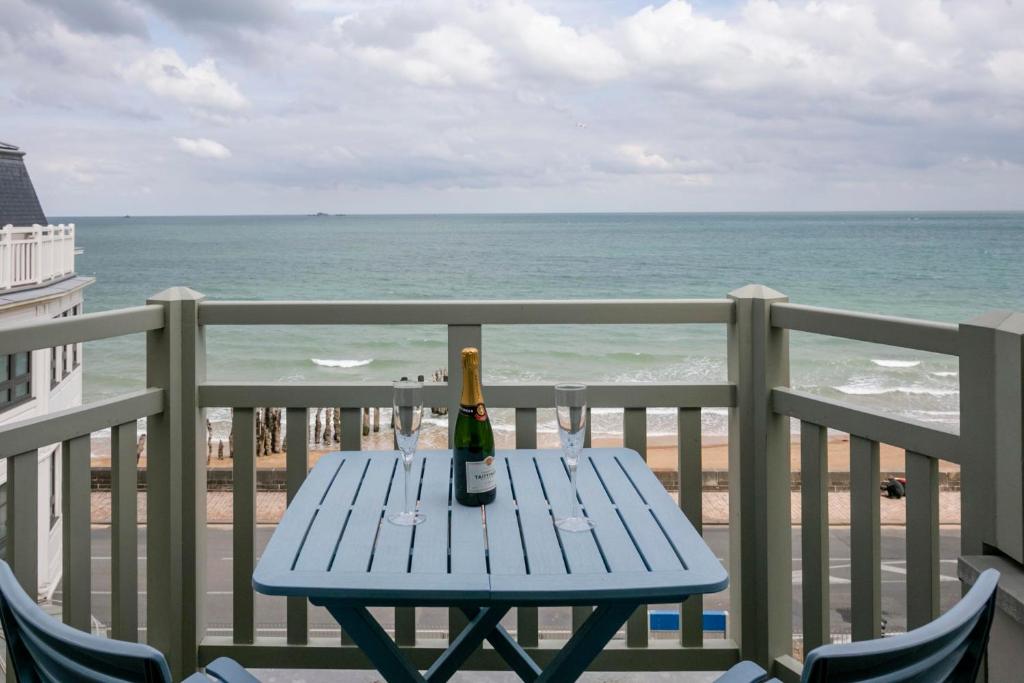 圣马洛Le Grand Sillon的海滩景阳台野餐桌上的一瓶葡萄酒