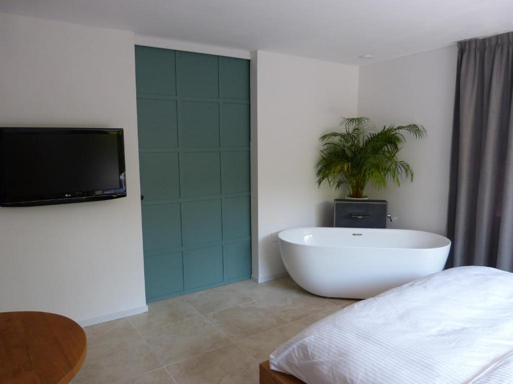 NoordwoldeHuize Triangel - Wellness studio met sauna的一间带浴缸、电视和植物的卧室