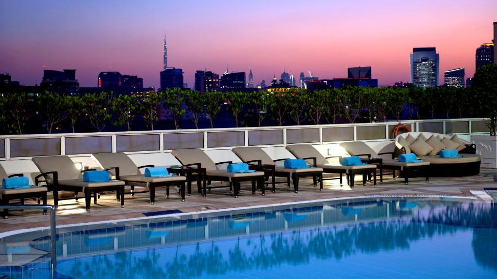 迪拜迪拜迪尔拉皇冠假日酒店的酒店庭院设有游泳池和城市天际线