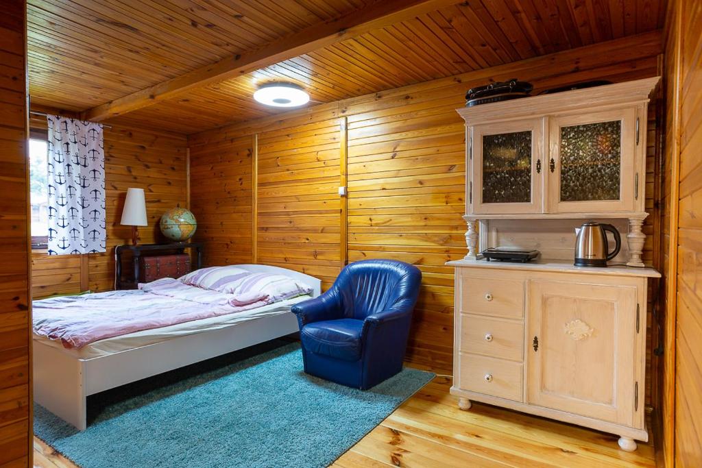 StęszewAB Domki całoroczne nad jeziorem的一间卧室配有一张床和一张蓝色椅子