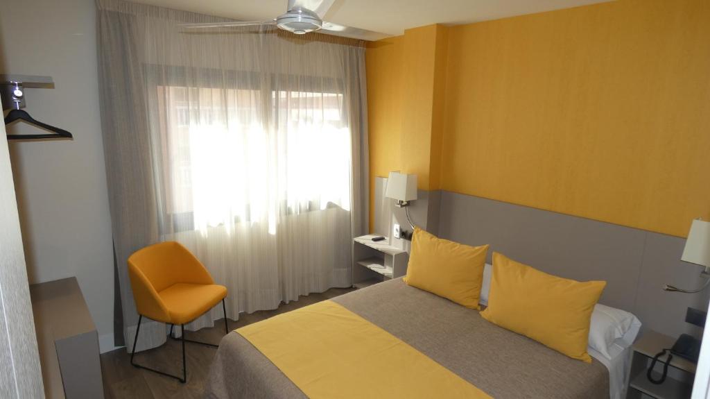 马拉加宙斯酒店的卧室配有床、椅子和窗户。