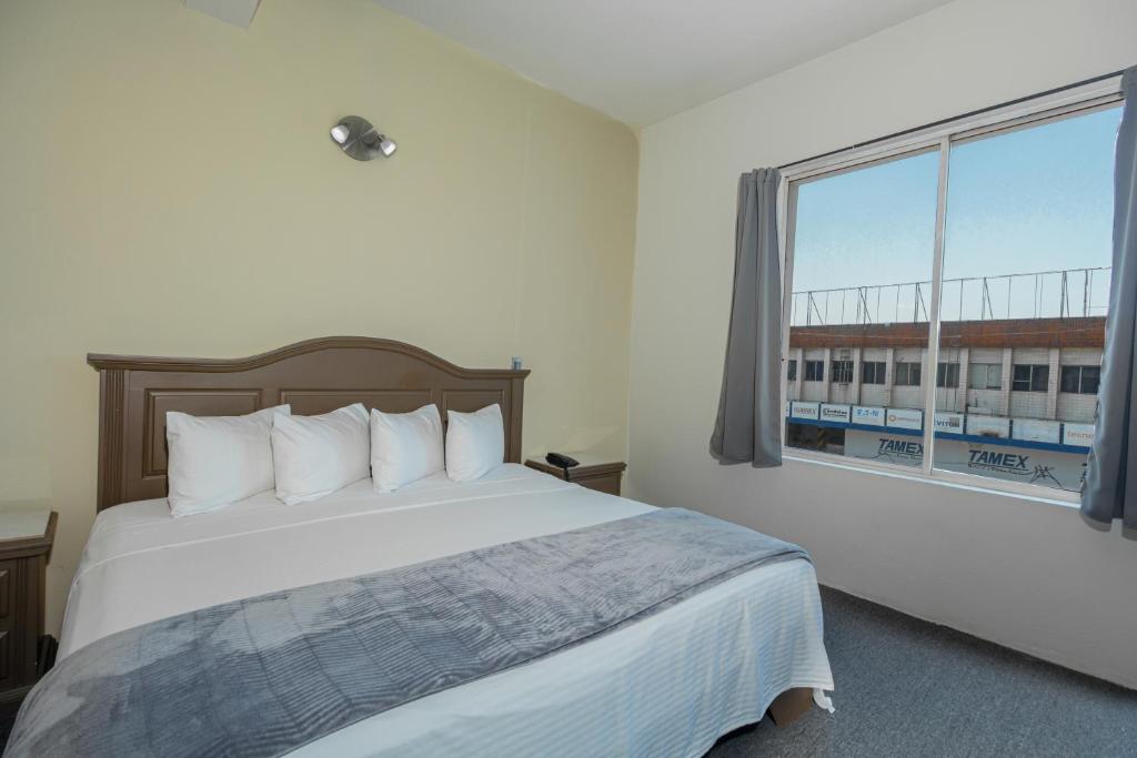 蒙特雷Hotel Plaza del Arco - Monterrey的一间卧室设有一张床和一个大窗户