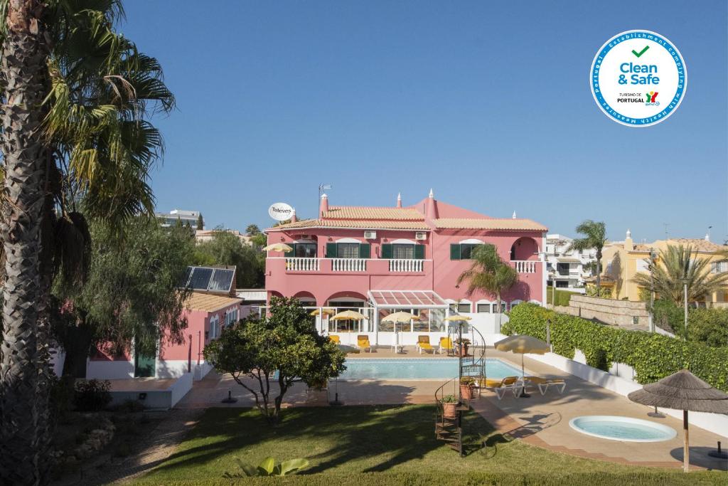 拉戈斯索拉德莫斯酒店的粉红色的房子,前面设有一个游泳池