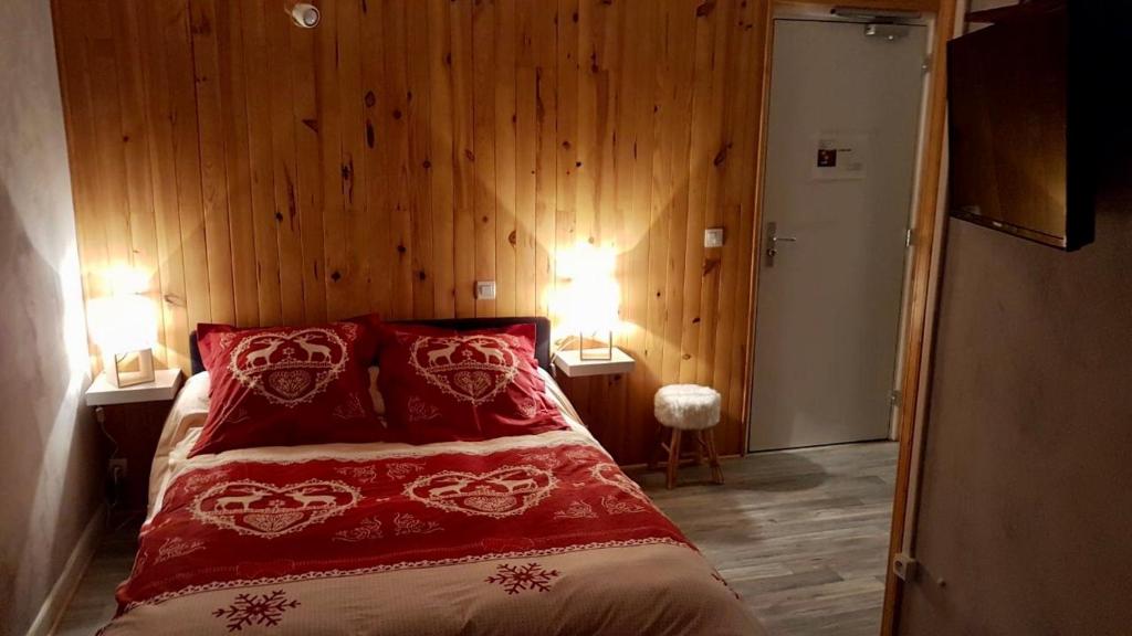 Condamine-ChâtelardLa Condaminoise的一间卧室配有一张带红色枕头的床和木墙