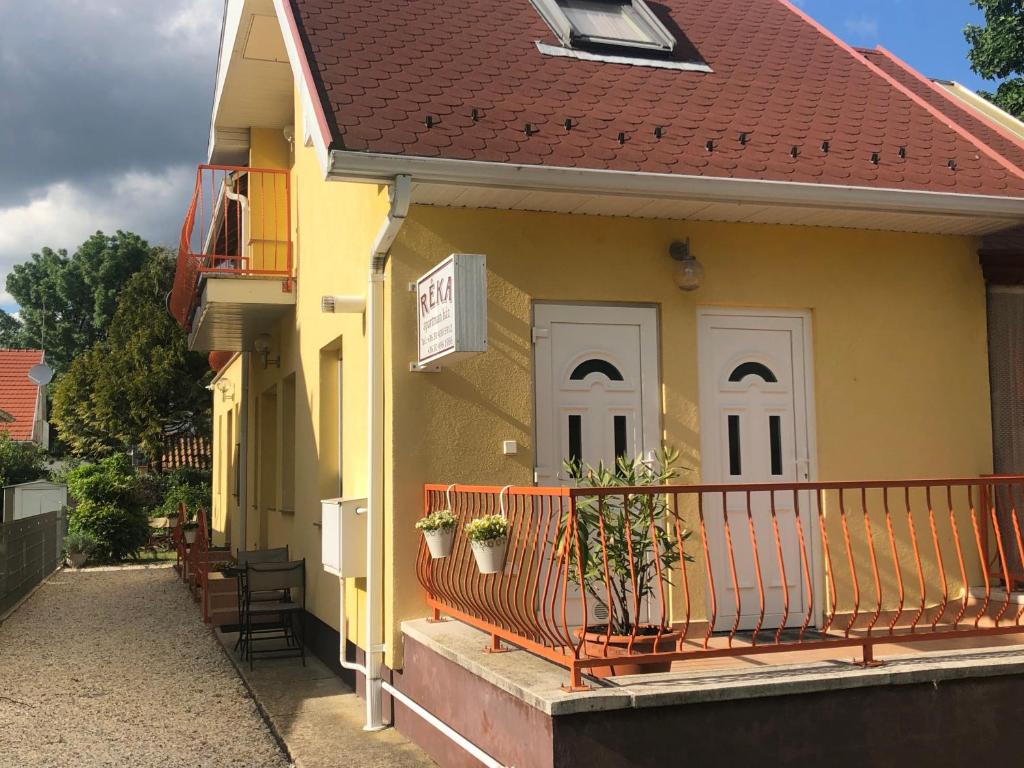 比克Réka Apartmanház的黄色的房子,设有白色门和阳台