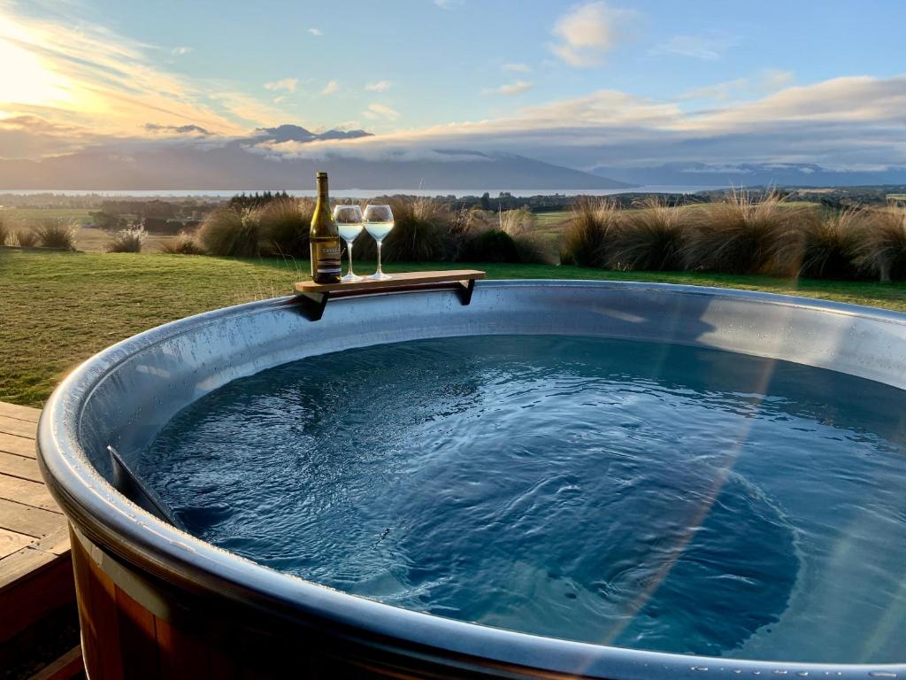 蒂阿瑙Fiordland Eco-Retreat -- Panoramic Views -- Hot Tub的热水浴池,配有1瓶葡萄酒和2杯