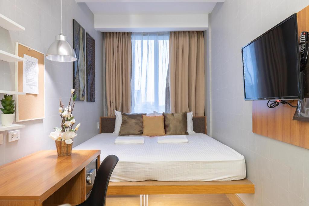马尼拉Selah Pods Hotel Manila的一间卧室配有一张床、一张书桌和一台电视