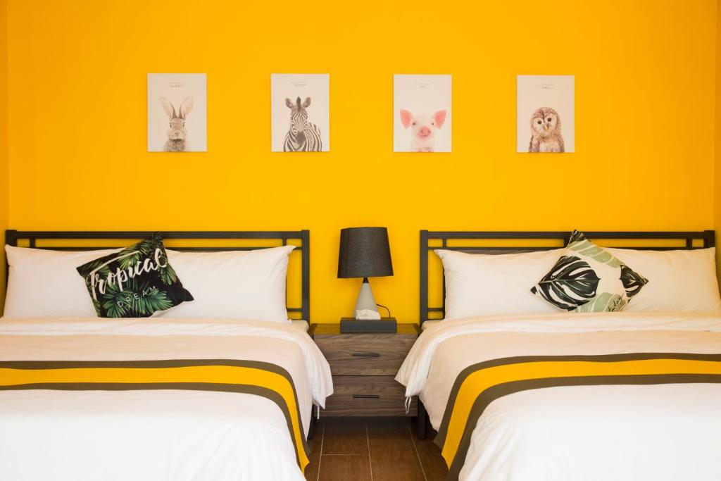 马公綠光海岸民宿的黄色墙壁客房的两张床