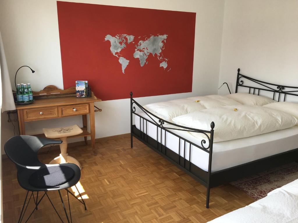 罗曼斯霍恩Lakelodge-Romanshorn 2的一间卧室配有一张床和一张书桌,墙上挂着一张世界地图