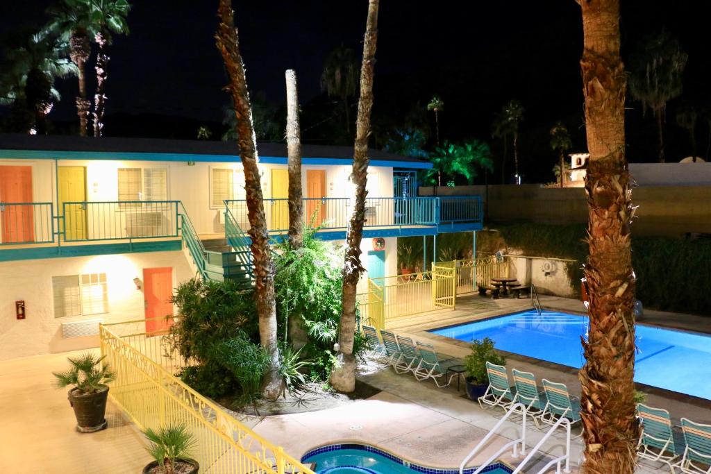 棕榈泉Adara Palm Springs的夜间带游泳池和棕榈树的度假村
