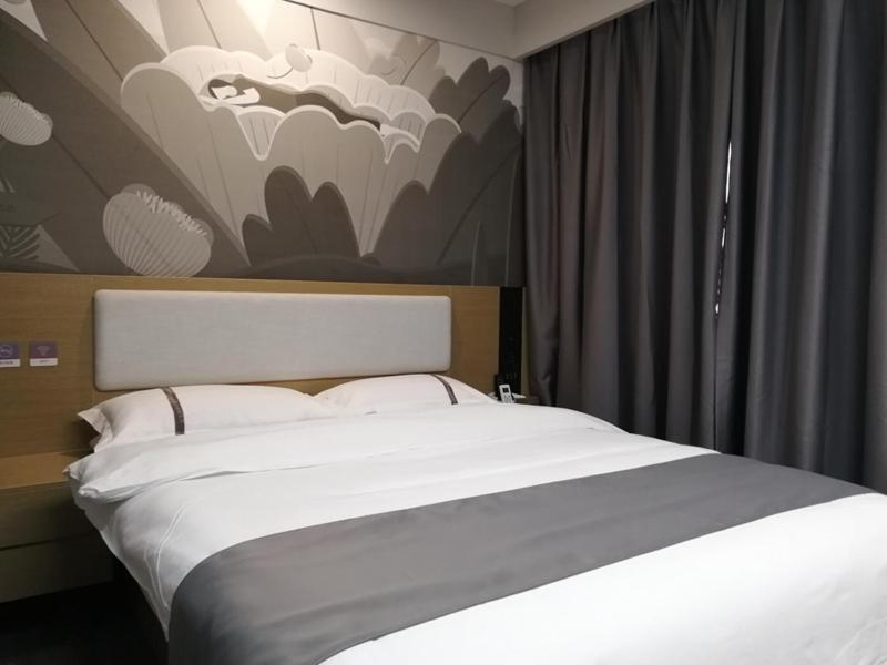 扬州尚客优酒店江苏扬州邗江区汊河大学城店的卧室配有一张白色床,墙上挂有绘画作品
