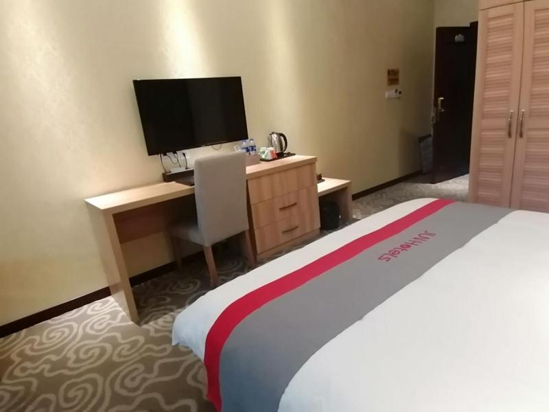 简阳骏怡连锁四川成都简阳简城镇建设路店的酒店客房配有一张床和一张书桌及一台电视