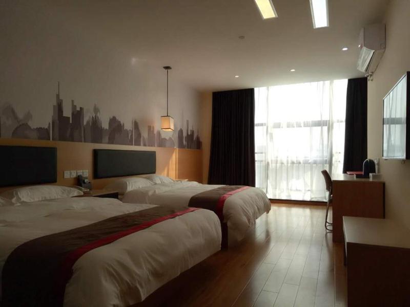 池州尚客优酒店安徽池州站前区火车站店的酒店客房设有两张床和窗户。