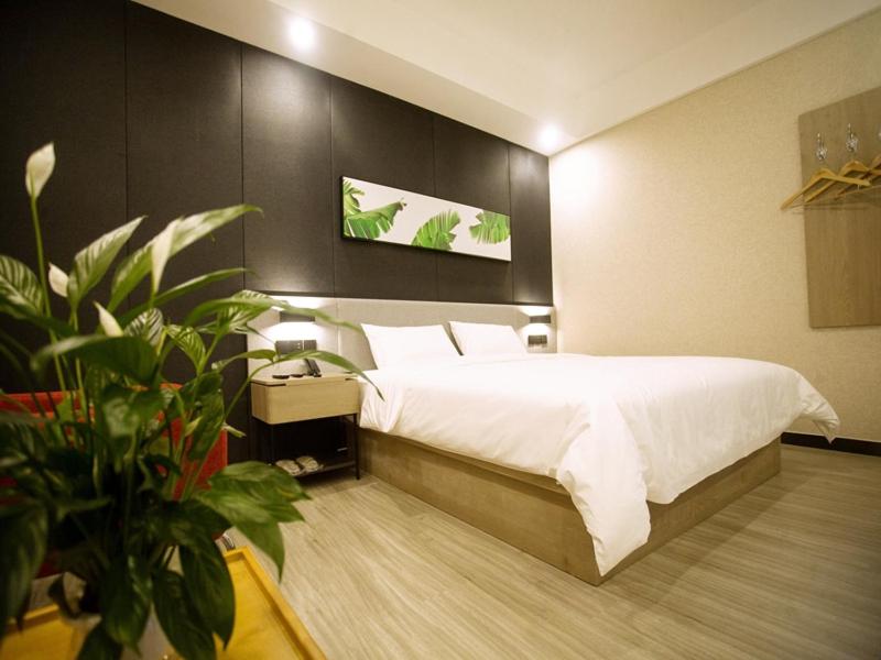 包头尚客优品内蒙古包头青山区中环国际店的卧室配有白色大床和植物