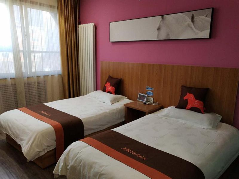 兰州骏怡连锁甘肃兰州城关区兰州大学店的配有粉红色墙壁的酒店客房的两张床